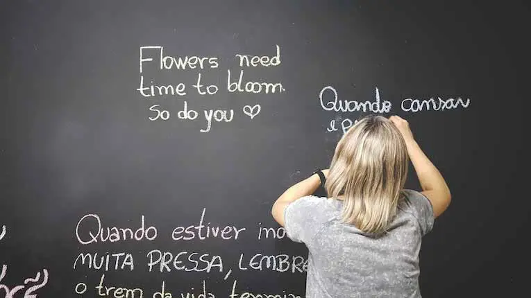 person writing in Spanish on a chalkboard