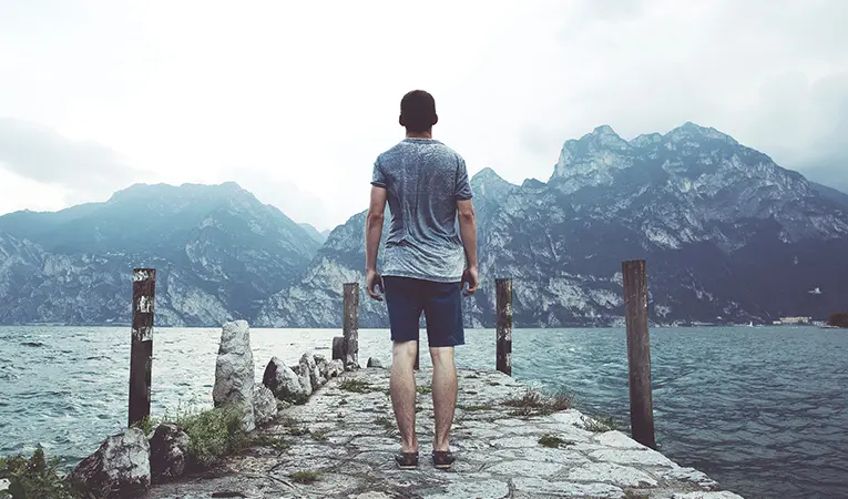Man standing on a bridge near the mountains