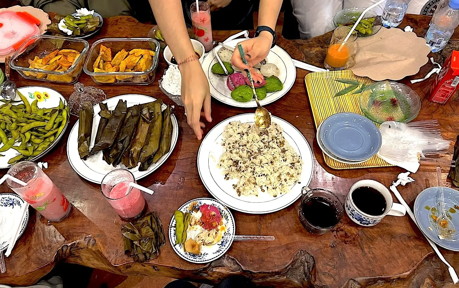 A diverse group of people stands in a Balinese temple, hands in prayer position, smiling. The image conveys a sense of peace and unity.
