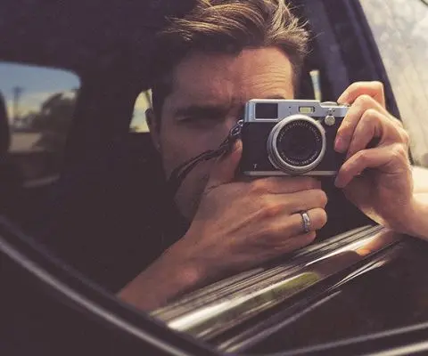 Man taking photo in rearview mirror in car