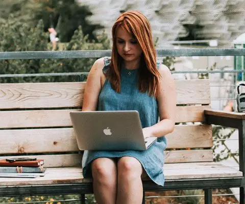 Woman sitting on a laptop in a park