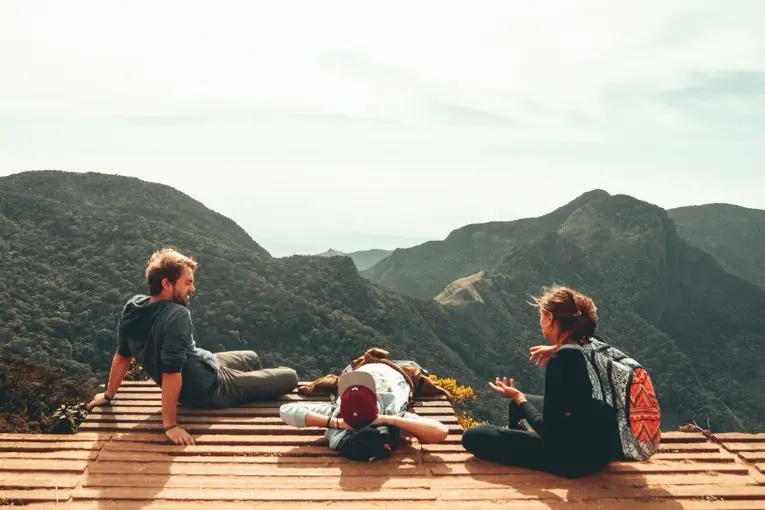 three people by a balcony overlooking mountains