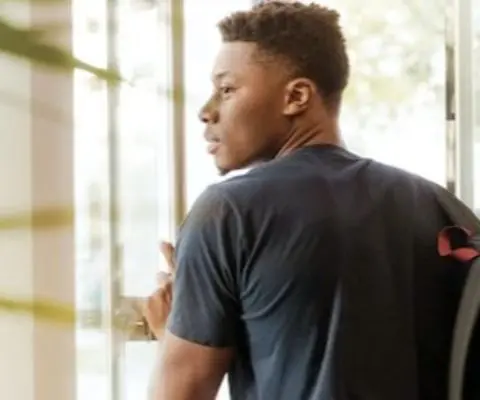 person-wearing-backpack holding-open-glass-door-featured-photo