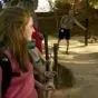 Lady with a backpack, smiling while holding on railing at a zoo