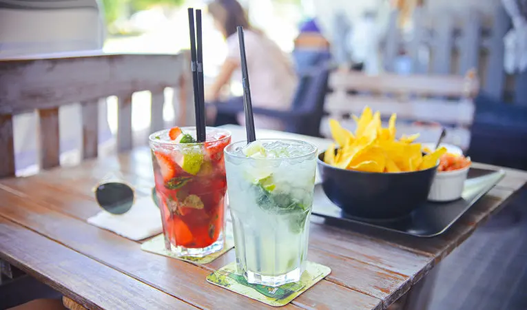 fruity cocktails with straws on a patio table with chips and salsa