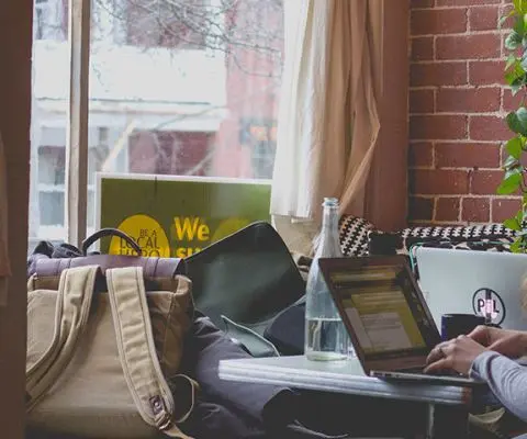 woman working on laptop in cafe with windows