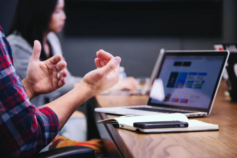 close up of person’s hands with laptop and phone on a table