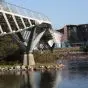 View under a bridge at waters edge looking at a building 