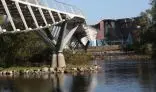 View under a bridge at waters edge looking at a building 